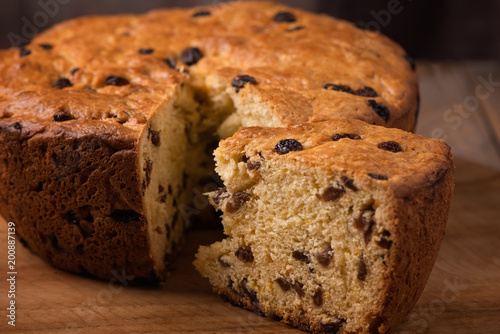 home made cake with raisins with slice on wooden plate close up