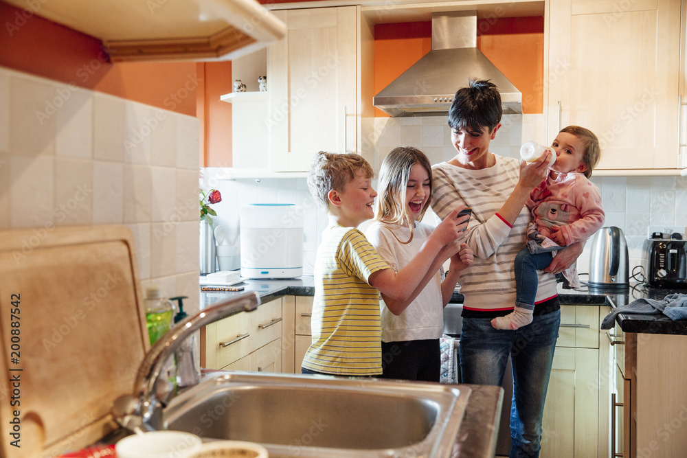 Naklejka premium Multitasking Mum with her Children at home