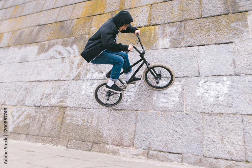 BMX rider rides a bicycle on the wall. A young man is doing tricks on BMX. BMX freestyle