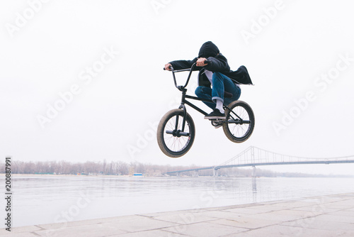 BMX freestyle. The toddler jumps on a BMX bike. BMX rider makes tricks on the background of the river