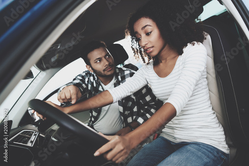 African american family at car dealership. Mother and father are trying out new car. © freeograph