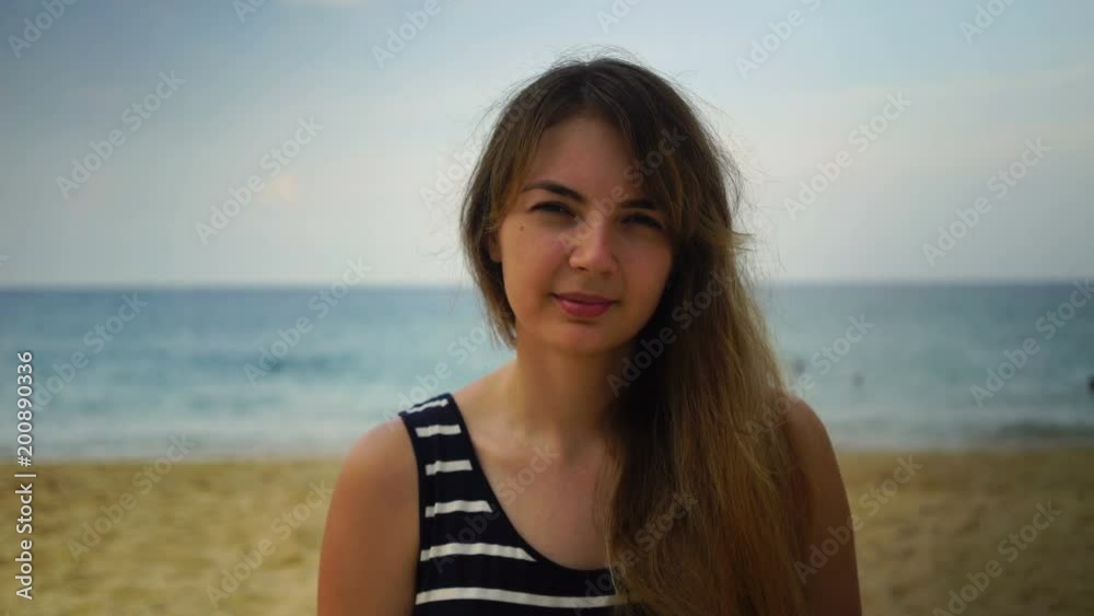 close-up portrait of a young girl looking at the camera on the beach near the ocean. close-up portrait of a young girl looking at the camera on the beach near the ocean.