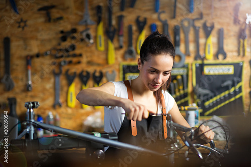 Young woman working in a bicycle repair shop 