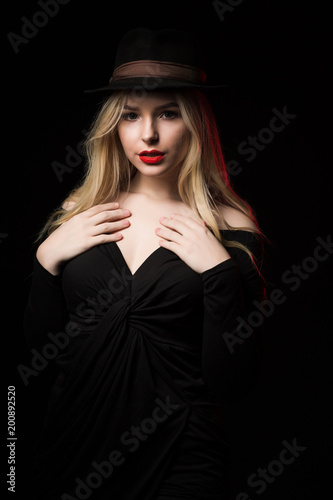 Cool blonde model with red lips posing over a dark background