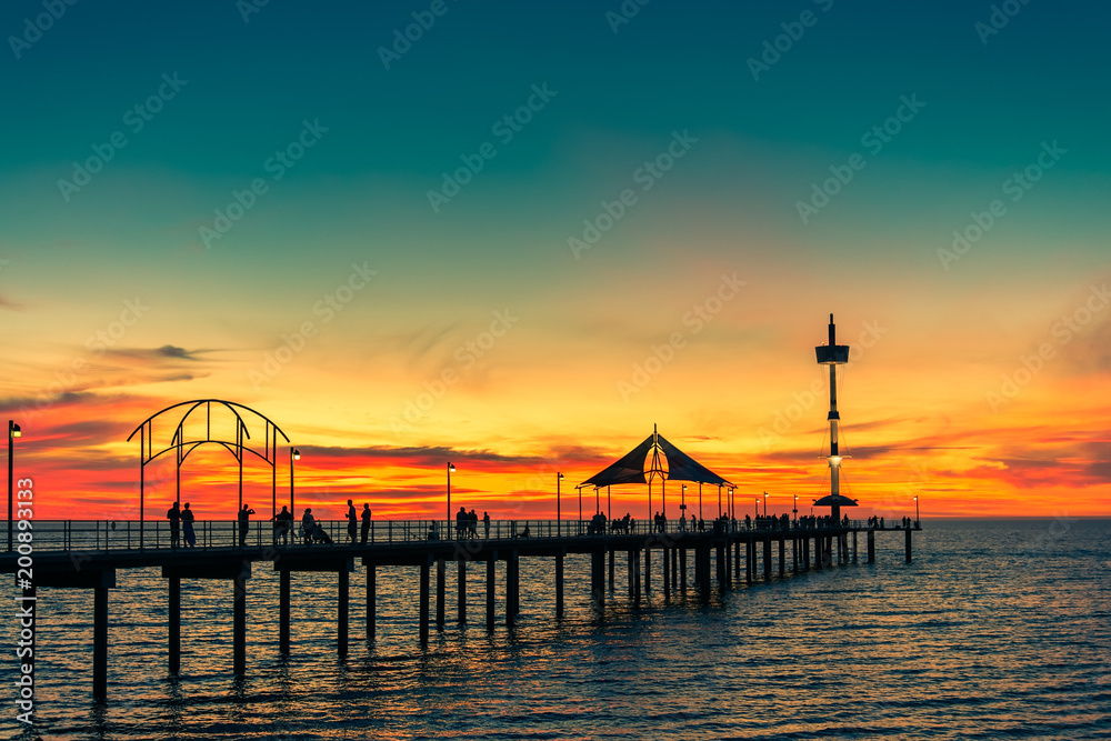 People walking along Brighton jetty at sunset
