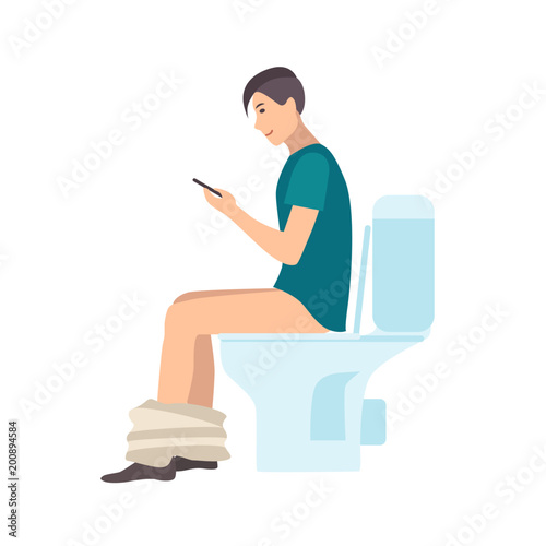 Young man sitting on toilet, holding smartphone and surfing internet while pooping isolated on white background
