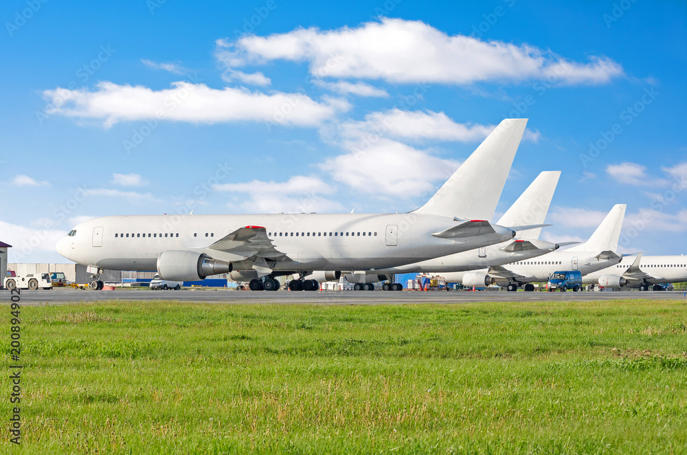 Row of passenger aircraft airplane parked at the airport, on service before departure. Row of passenger aircraft airplane parked at the airport, on service before departure.