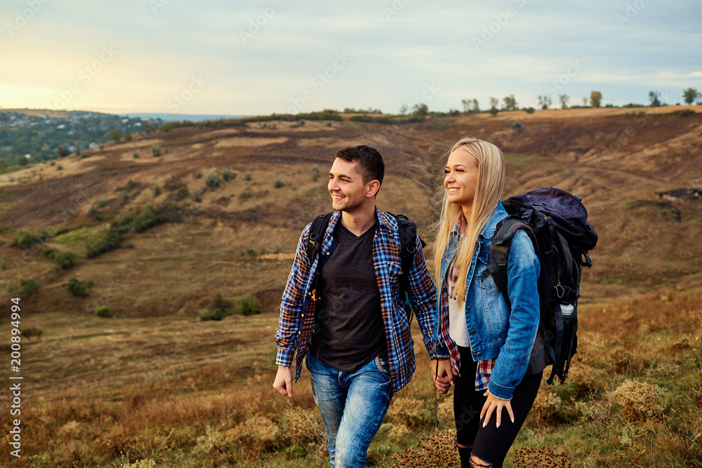 Young couple of tourists with backpacks on the nature.