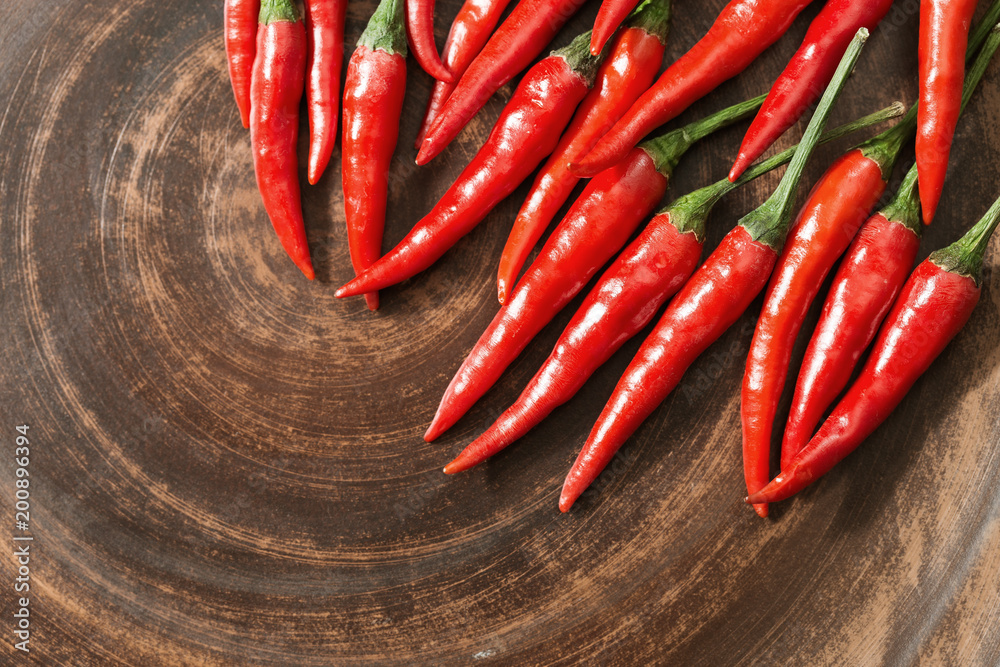 Red hot chili peppers on brown clay flat plate. Copy space. Top view. Food background.