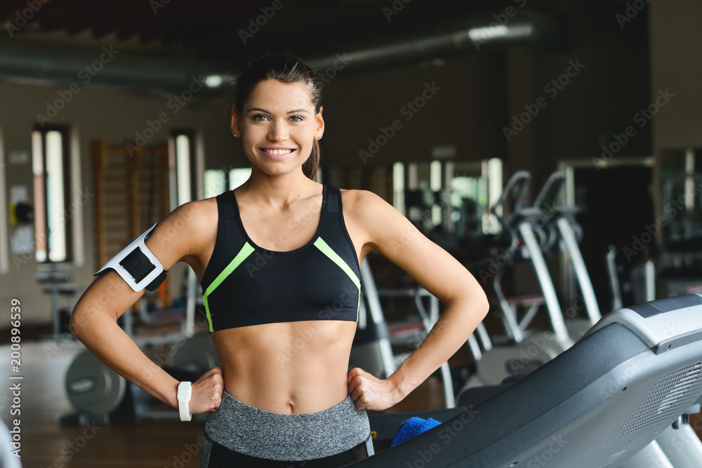 A beautiful woman (girl) smiles while she is training in the gym. Concept: Sport, passion, happiness.