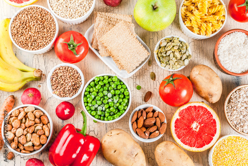 Diet food background concept, healthy carbohydrates (carbs) products - fruits, vegetables, cereals, nuts, beans, light concrete background above