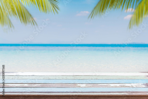 Fototapeta Naklejka Na Ścianę i Meble -  Empty wood table top and blurred Palm tree summer beach with blue sea and sky background. - can used for display or montage your products.
