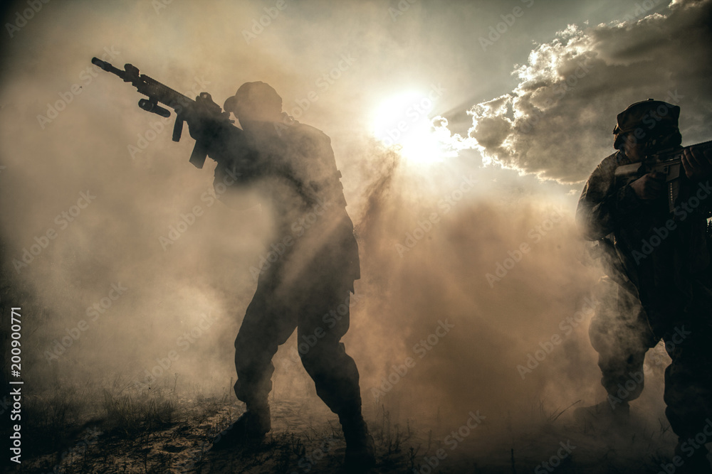 Obraz premium United States Marines in action. Military equipment, army helmet, warpaint, smoked dirty face, tactical gloves. Military action, desert battlefield, smoke grenades