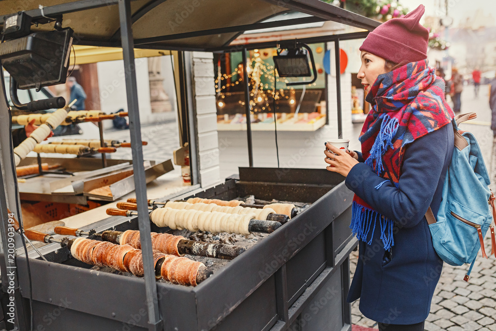 Woman tourist chooses a Trdelnik in a bakery on the street market in Prague