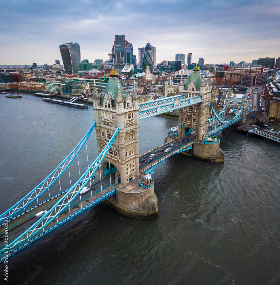London, England - Aerial panormaic view of the iconic Tower Bridge and Tower of London on a cloudy moring with skyscrapers of the financial Bank District at background