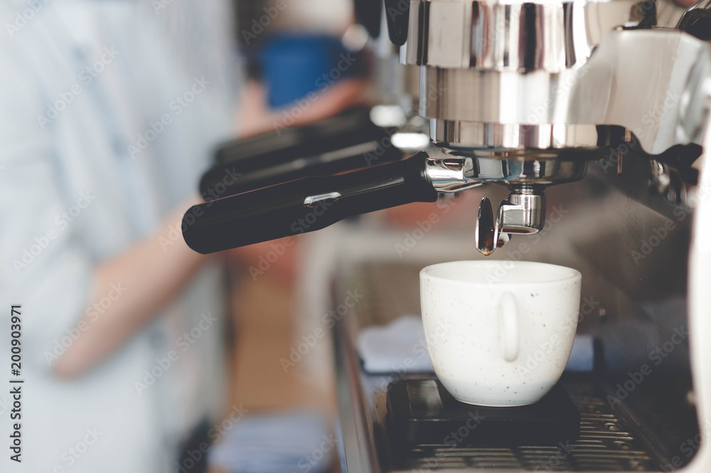 A Cup of espresso standing on the coffee machine, on the background of the baristas A Cup of espresso standing on the coffee machine, on the background of the baristas