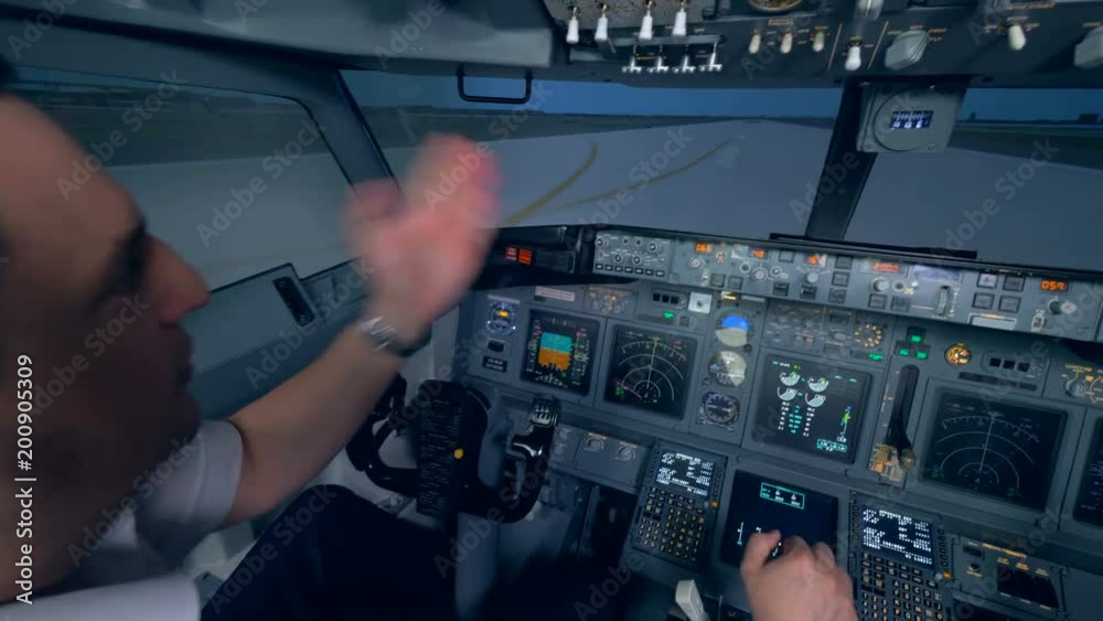 A plane goes on a runway, two pilots in a flight simulator cockpit. A plane goes on a runway, two pilots in a flight simulator cockpit.