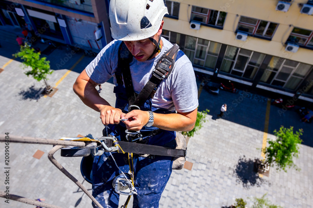 Industrial climber is washing, cleaning facade of a modern office building Industrial climber is washing, cleaning facade of a modern office building