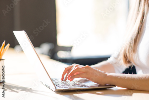 Close up Image of Woman Hands Typing on the Laptop Keyboard in Front of Big Window.