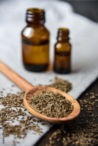 caraway oil and seeds on wooden spoon and essential oil