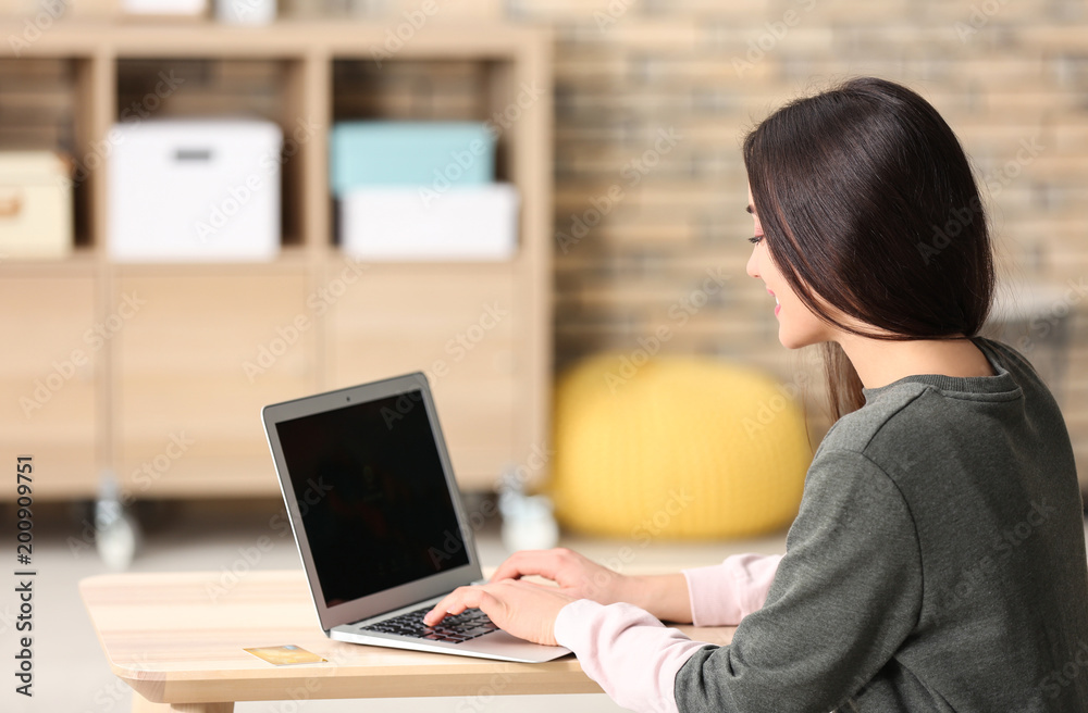 Fototapeta premium Young woman shopping online with laptop at table
