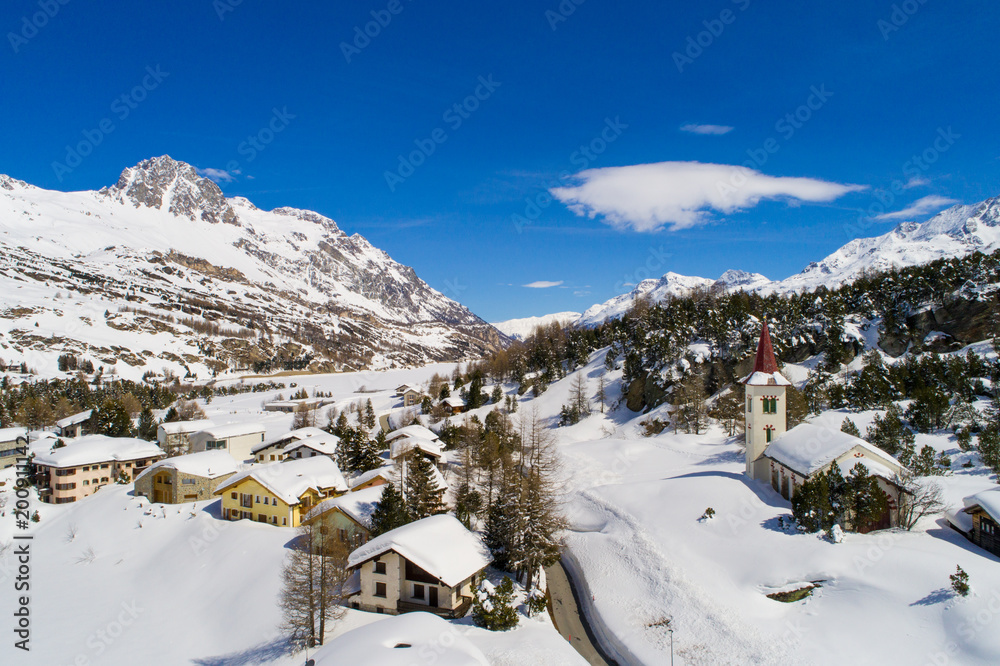 Village covered with snow in the Swiss Alps. Valley of Engadine (Maloggia)