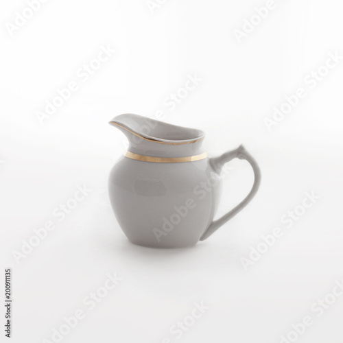 White vintage porcelain sauceboat with a gold border on white background