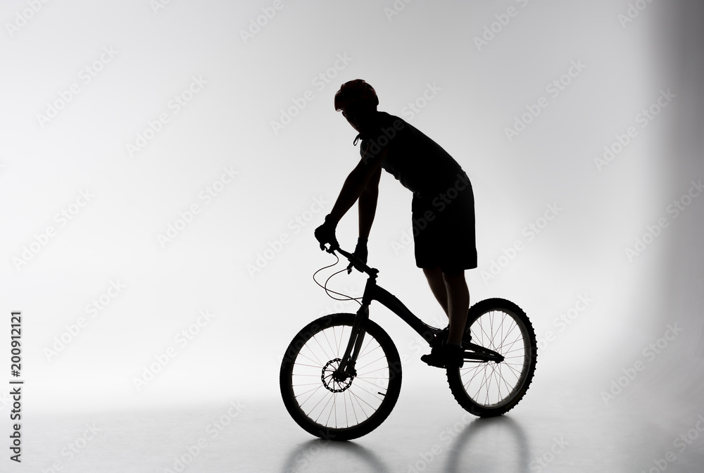 Fototapeta premium silhouette of trial cyclist in helmet balancing on bicycle on white