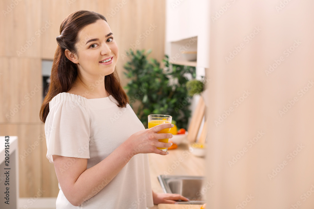 Vitamin C. Happy enthusiastic woman gazing at camera while holding glass of orange juice Vitamin C. Happy enthusiastic woman gazing at camera while holding glass of orange juice
