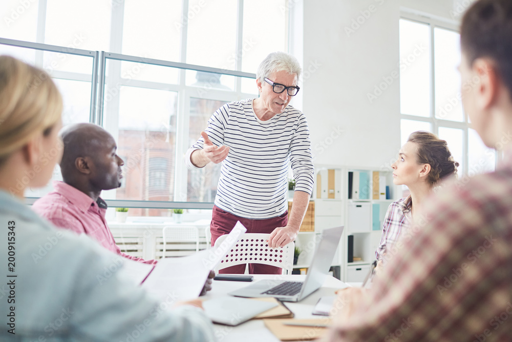 Obraz premium Senior businessman communicating with business team during a meeting