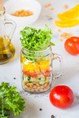 Salad in a jar. Homemade healthy salad from chickpea, tomato, yellow paprika, cucumber and green lettuce
