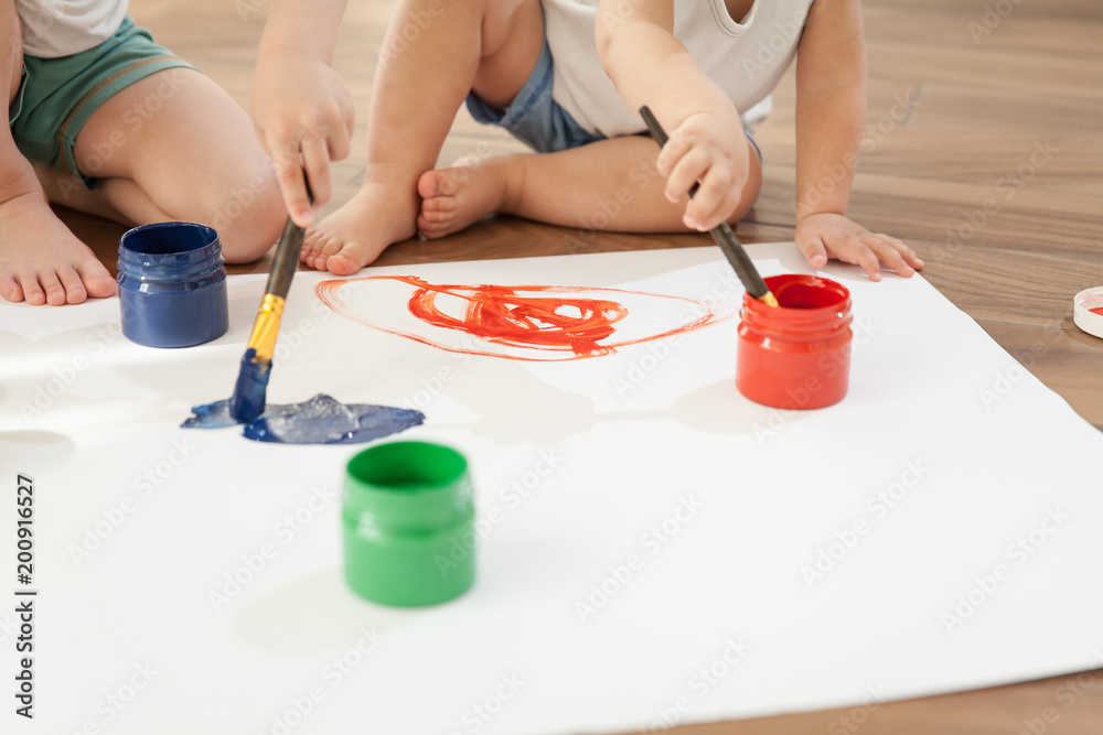 Children draw bright colors on paper, sitting on the floor Children draw bright colors on paper, sitting on the floor
