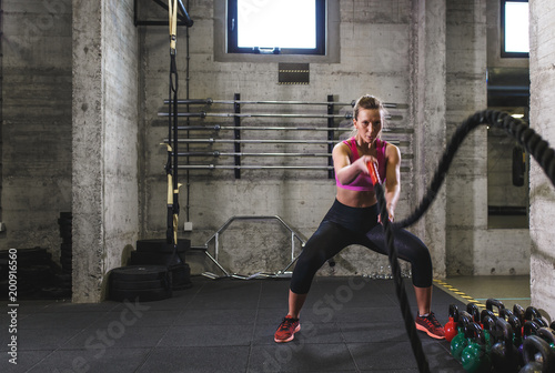 Fototapeta Naklejka Na Ścianę i Meble -  Fitness woman exercise in the gym with battle rope.