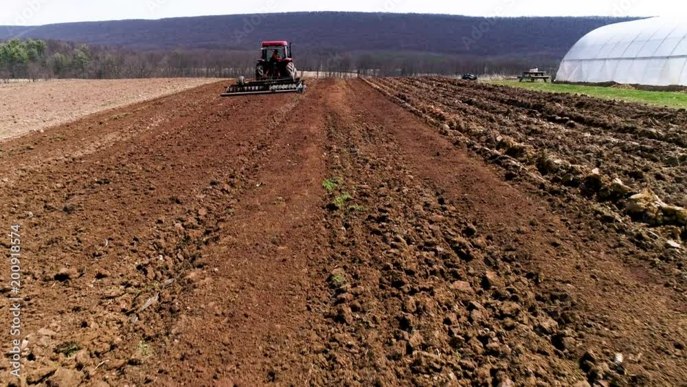 Aerial camera moving just above the dirt and catching up to a tractor pulling a plow. Aerial camera moving just above the dirt and catching up to a tractor pulling a plow.