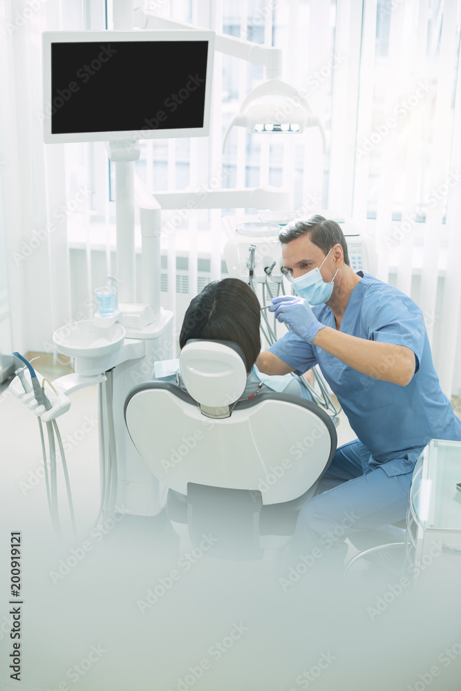My cabinet. Experienced male dentist wearing a uniform and examining his patients teeth My cabinet. Experienced male dentist wearing a uniform and examining his patients teeth