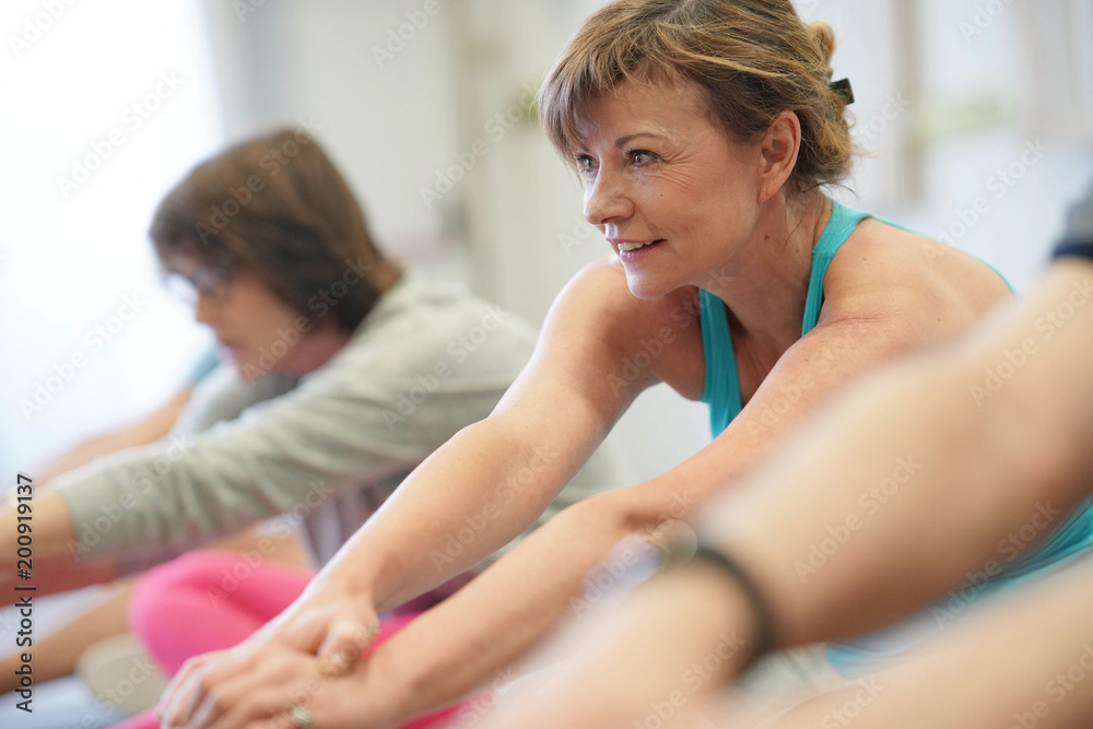 Portrait of senior woman in fitness class exercising on floor