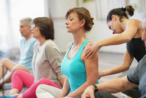 Group of senior people in fitness room exercising with coach