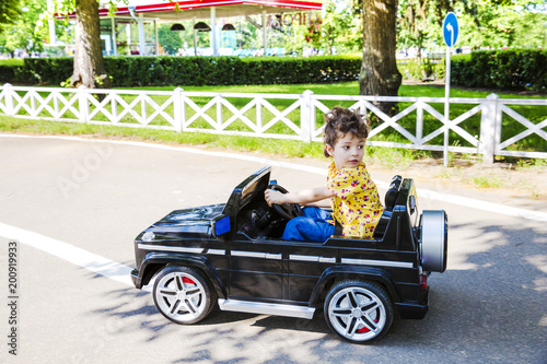 Amusement Park, a funny boy rides on a toy electric car on a sunny summer day © kravik93