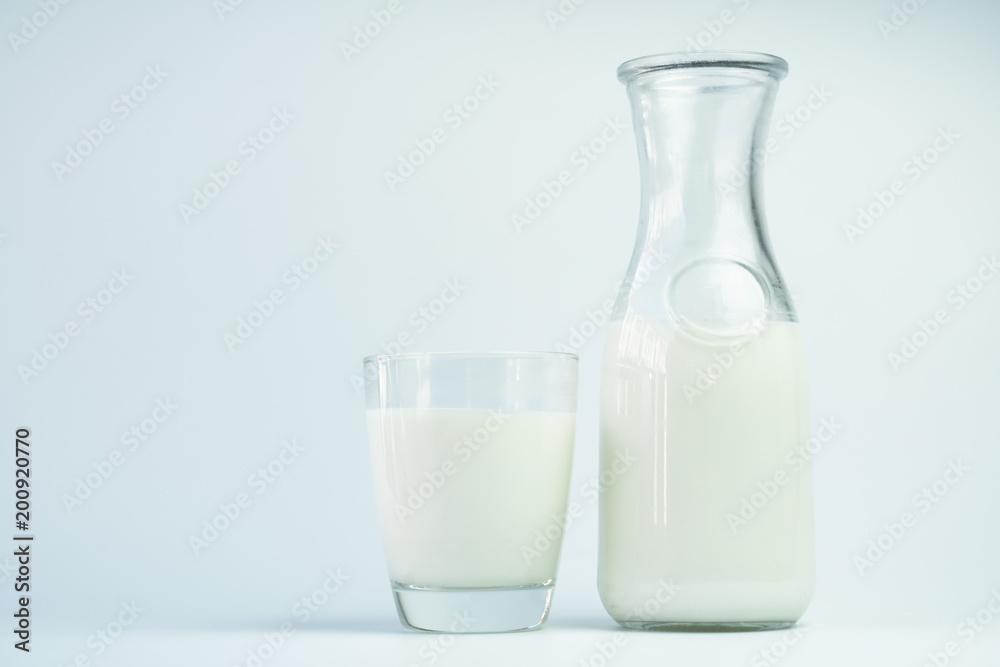 Natural whole milk in a jug and a glass isolated on a white background closeup Natural whole milk in a jug and a glass isolated on a white background closeup