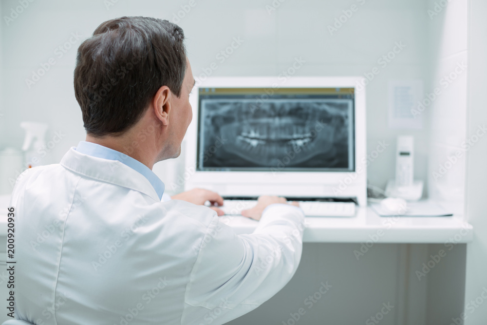 Amazing device. Professional male dentist wearing a uniform and working on his new device