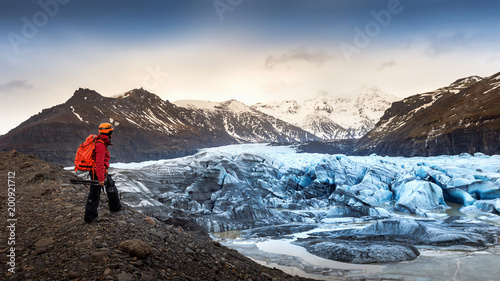 professional photographer with camera and tripod in winter. professional photographer looking to glacier in Iceland.