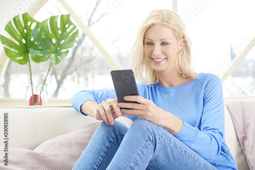 Relaxed woman relaxing at home and using cell phone and making a call 