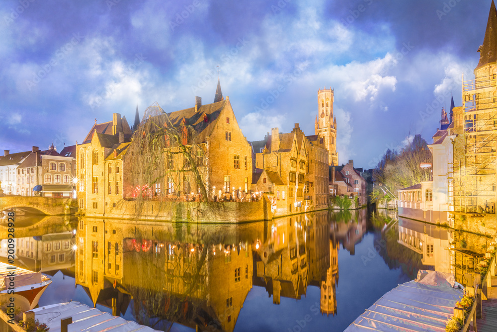 Fototapeta premium Wieża dzwonnicy i średniowieczne budynki wzdłuż kanału w Brugii, Belgia