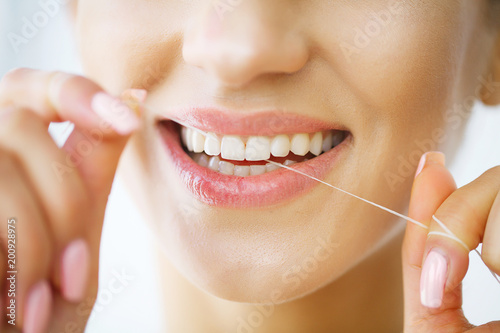 Teeth Care. Beautiful Smiling Woman Flossing Healthy White Teeth. High Resolution Image