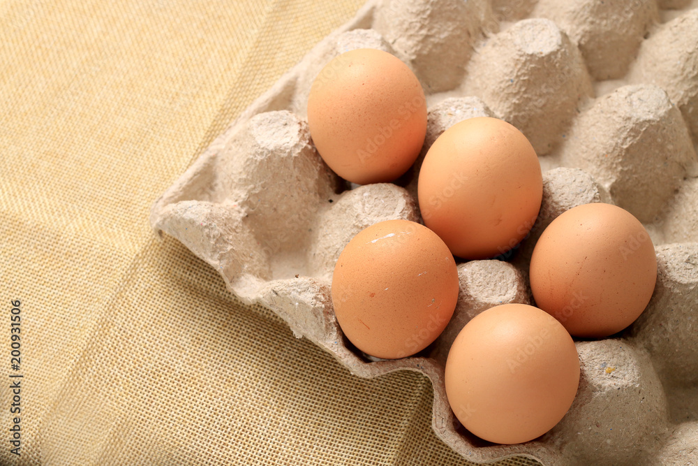 Fresh chicken eggs In the thirty box paper and have empty space for egg on cream fabric background. Fresh chicken eggs In the thirty box paper and have empty space for egg on cream fabric background.