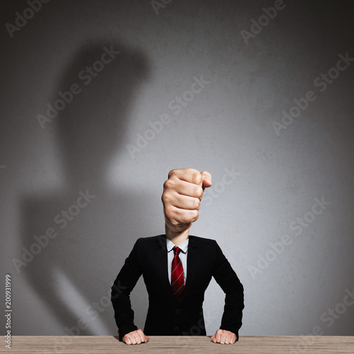 The man in a suit with a head in the form of a fist. Metaphor of an angry boss.