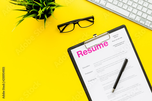 Empoyment concept. Resume on pad near pen and glasses on yellow background top view copy space