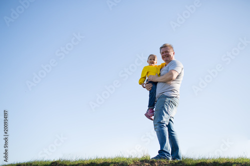 dad and daughter on the grass against the sky