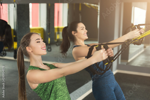 Women performing TRX suspension training in gym
