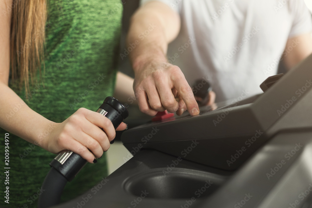 Fitness coach helps woman on elliptical trainer